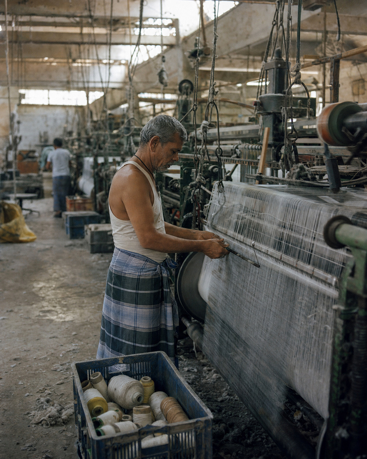 Weaver adjusting warp threads on a power loom